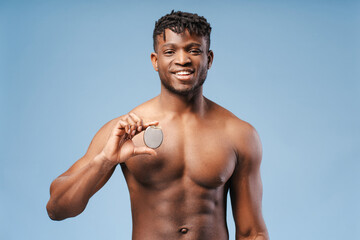 Handsome smiling young African American man holding cardiac pacemaker, ICD