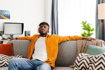 Overjoyed African American man listening to music in headphones, enjoying