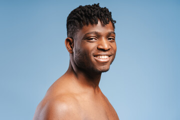 Closeup, portrait of smiling African American man, athlete with muscular body, naked torso