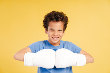 Cute handsome African American boy boxer wearing white boxing gloves looking at camera