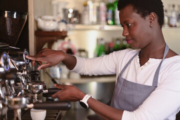 Skilled barista in an apron operates an espresso machine in a modern cafe setting