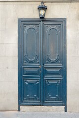 Vintage weathered door painted of dark blue colour with light lamp on top downtown Madrid, Spain