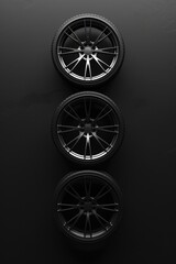 Image of three black wheels on a dark surface. Suitable for automotive industry