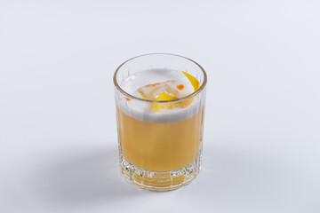 Alcoholic cocktail whisky sour with ice, orange and foam on white background