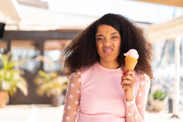 Young African American woman with a cornet ice cream at outdoors with sad expression