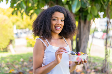 Young African American woman holding a bowl of fruit at outdoors