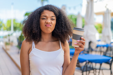 Young African American woman holding a take away coffee at outdoors with sad expression