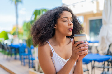 Young African American woman at outdoors holding a take away coffee