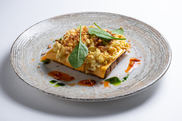 Closeup of toasted bread with scrambled egg, cheese and green leaves on plate