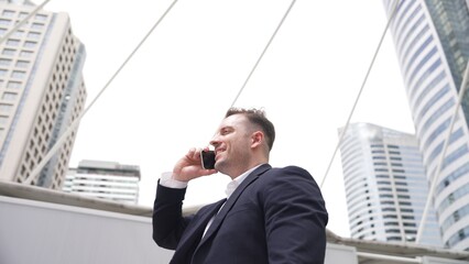 Smart caucasian businessman calling his colleague to plan financial strategy while standing at...