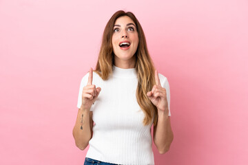 Caucasian woman isolated on pink background surprised and pointing up