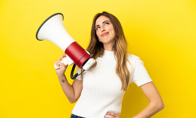 Caucasian woman isolated on yellow background holding a megaphone and thinking