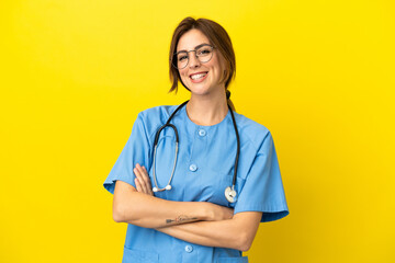 Surgeon doctor woman isolated on yellow background keeping the arms crossed in frontal position