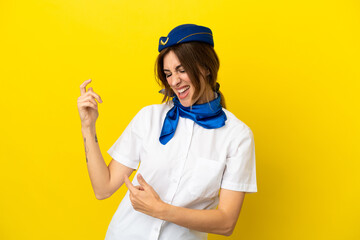 Airplane stewardess woman isolated on yellow background making guitar gesture