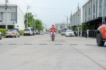 Fototapeta premium Delivery rider on red motorbike with insulated food box parked outdoors