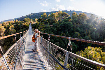 Obraz premium young girl in a hat stands on a suspension bridge and looks dreamily into the distance.