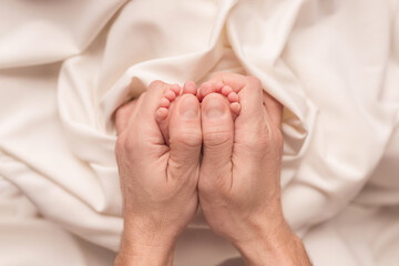 Baby feet of a newborn in dad's hands. On a white background.	