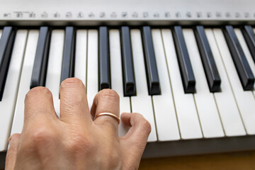 Woman's right hand above synthesizer keyboard