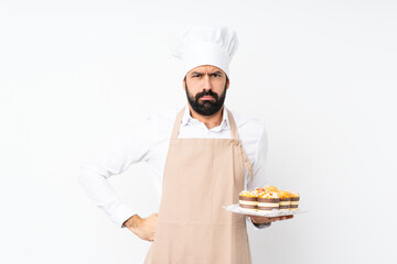 Young man holding muffin cake over isolated white background angry