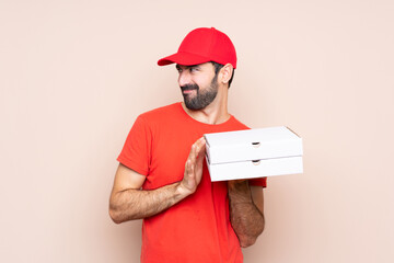 Young man holding a pizza over isolated background scheming something