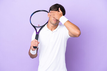 Handsome young tennis player man isolated on ocher background covering eyes by hands. Do not want...