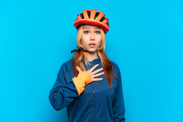 Young cyclist girl isolated on blue background surprised and shocked while looking right
