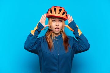 Young cyclist girl isolated on blue background with surprise expression