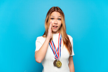 Teenager girl with medals over isolated background with surprise and shocked facial expression