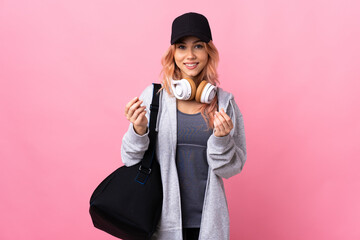 Teenager sport woman with sport bag over isolated background making money gesture