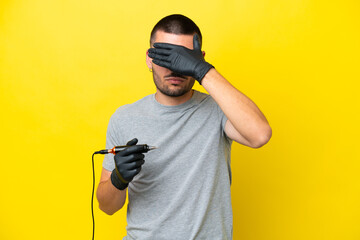 Tattoo artist caucasian man isolated on yellow background covering eyes by hands. Do not want to...