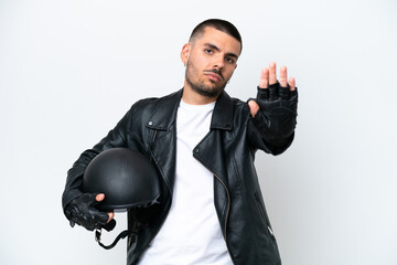 Young caucasian man with a motorcycle helmet isolated on white background making stop gesture