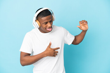 Young latin man isolated on blue background listening music and dancing