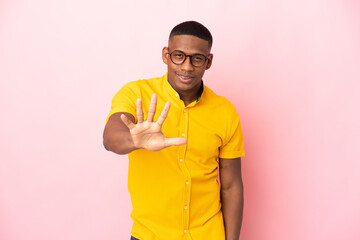 Young latin man isolated on pink background counting five with fingers