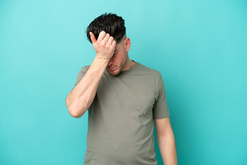 Young caucasian man isolated on blue background with headache