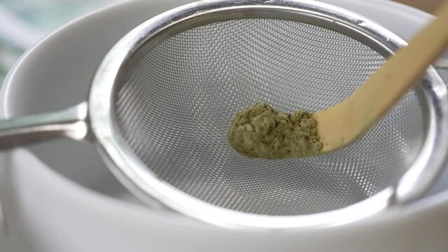 Close up and Slow Motion Footage of Small Spoon Scoop Matcha Powder to Sift in Fine Tea Sieve. Green Tea Ceremony Concept