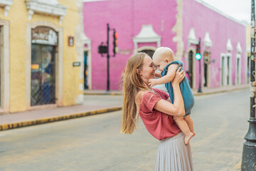 Mother and baby son tourists explore the vibrant streets of Valladolid, Mexico, immersing herself...