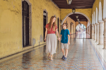 Mother and son tourists explore the vibrant streets of Valladolid, Mexico, immersing herself in the...
