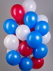 Large fountain of air balloons with helium in tricolor white blue red on a gray background