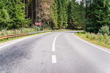 Empty asphalt street road in the mountains through the pine forest in Romania.