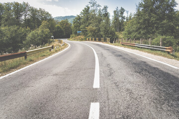 Empty asphalt street road in the mountains through the pine forest in Romania.