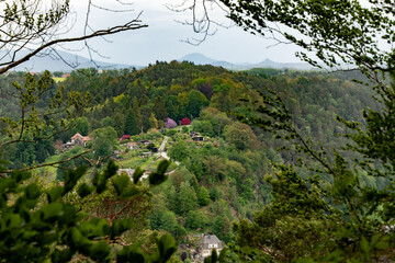 A view of a small town with houses and a cemetery. The town is surrounded by trees and the sky is cloudy