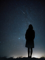 woman looking at the night sky wishing upon a falling star