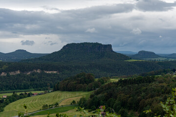 A mountain range with a cloudy sky in the background. The mountains are covered in trees and the...