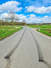 View of two black tire tracks made of burnt rubber from a car driving off quickly.