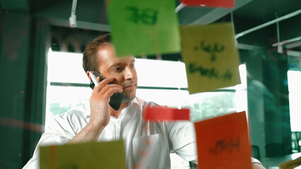 Professional businessman making phone call to customers while looking at marketing strategy idea...