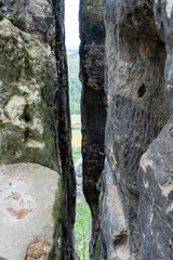A rock wall with a small opening in it. The opening is dark and narrow. The rock wall is made of black stone