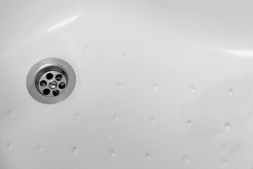 Detail of a ceramic white sink in a modern bathroom with chrome plated drain. Horizontal. For text.