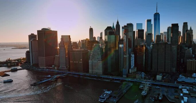 Sun setting behind the mighty skyscrapers in New York. Drone footage above the East River and Manhattan at sunset.