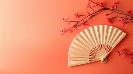 Wooden folding fan with red blossoms on vibrant orange background