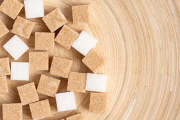 Cubes of cane and white refined sugar on wooden background.